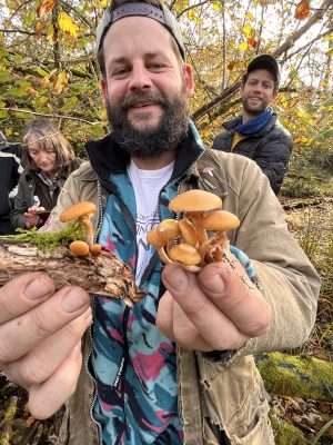 A wild food walk participant showing off mushrooms collected during a wild food walk