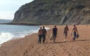 Five men enjoying a foraging walk along a shingle beach in dorset