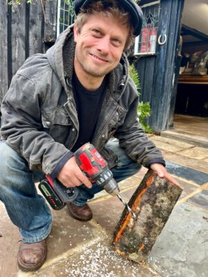 Man drilling and plugging mushroom logs