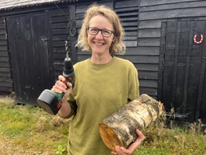 Woman smiling with mushroom log and drill