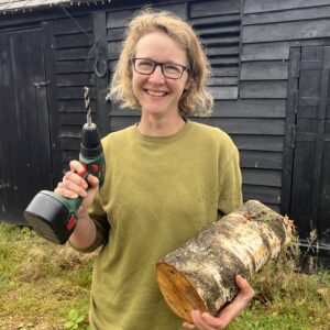 Woman smiling with mushroom log and drill